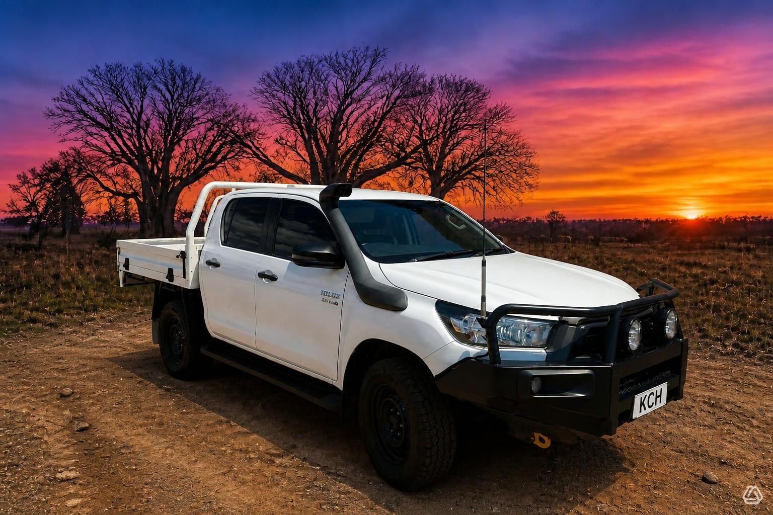 White Toyota Hilux dual-cab tray ute with bull bar and snorkel, boab trees at sunset
