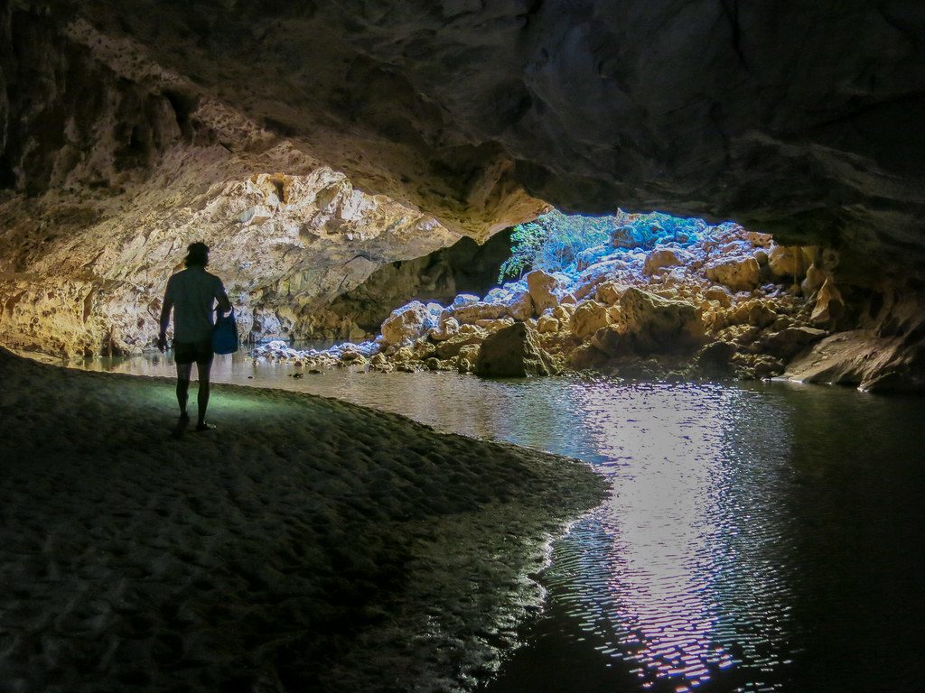 Walker with a torch wading through the cave passage at Tunnel Creek
